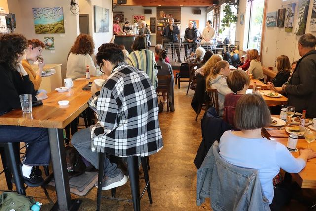 People seated around long tables at a café conversation event