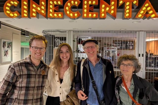Four people standing together beneath the illuminated Cinecenta sign