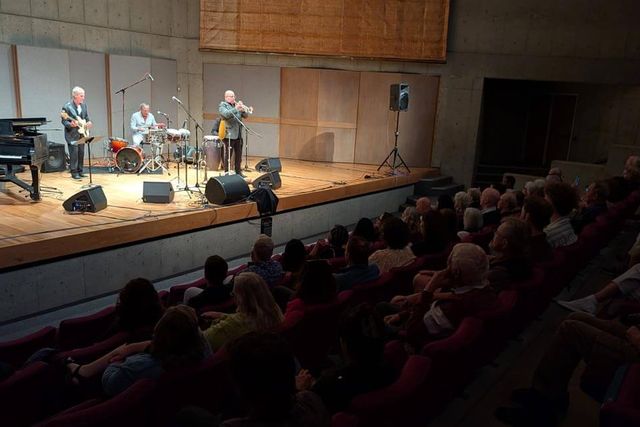 Musicians performing on the recital hall stage in front of a seated audience