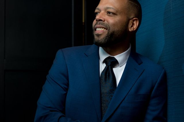 A singer in a blue suit performing under stage lighting